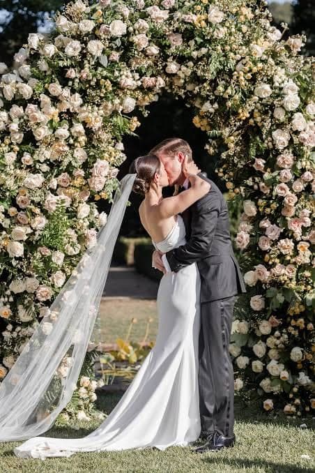Valeria y Emiliano bajo un arco de flores blancas